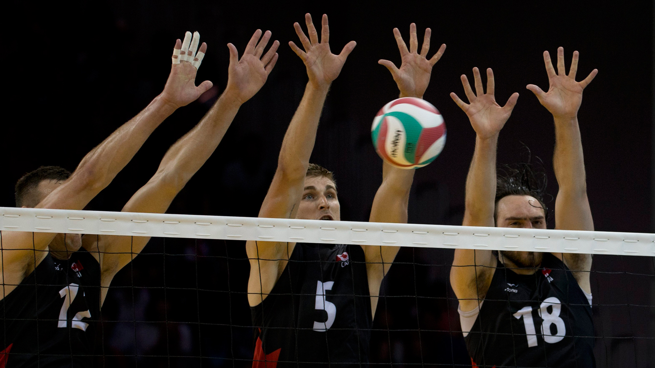 Canada's Rudy Verhoeff, center, jumps to block along with teammates Gavin Schmitt, left, and Nicholas Hoag in their men's volleyball preliminary against Mexico at TO2015